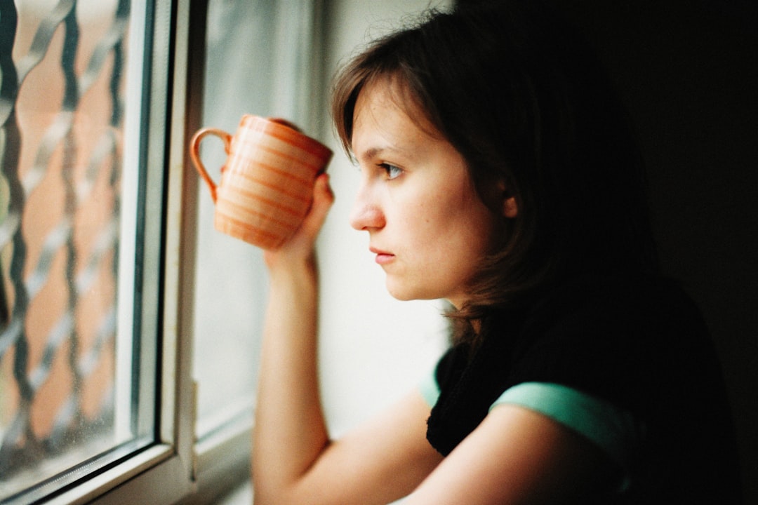 A woman taking a quiet moment alone with a cup, looking out a window
